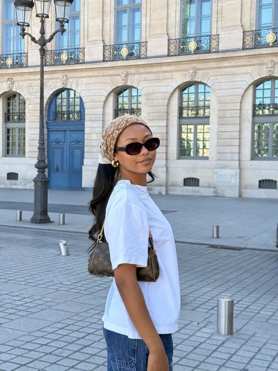 Mia in Place Vendôme in a white tee, sunglasses and a patterned headscarf
